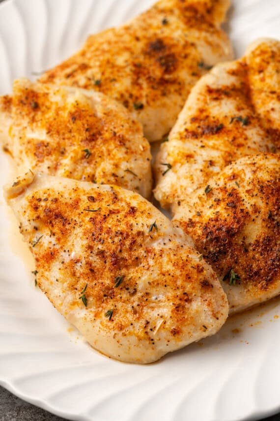 Baked chicken breasts on a large white platter.