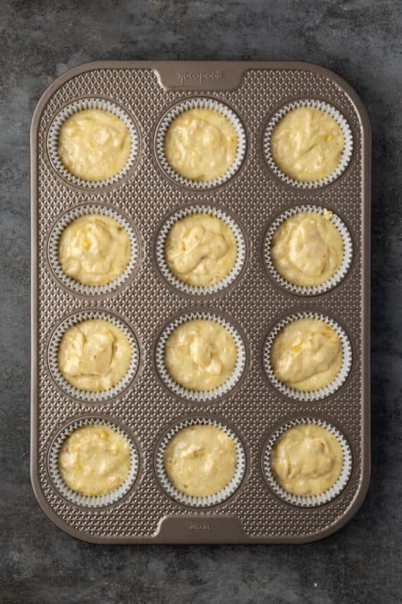 A lined 12-well cupcake tin filled with banana cupcake batter