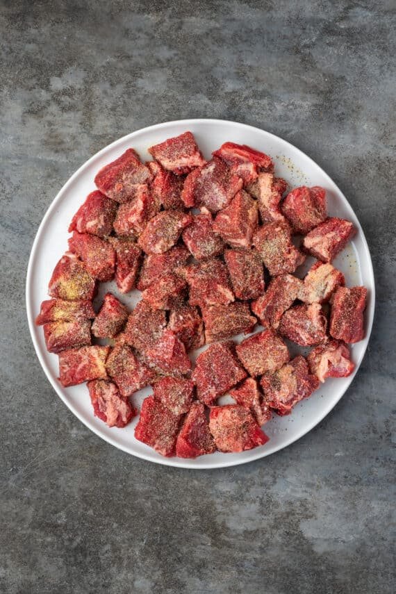 Seasoned cubed beef on a large round plate.