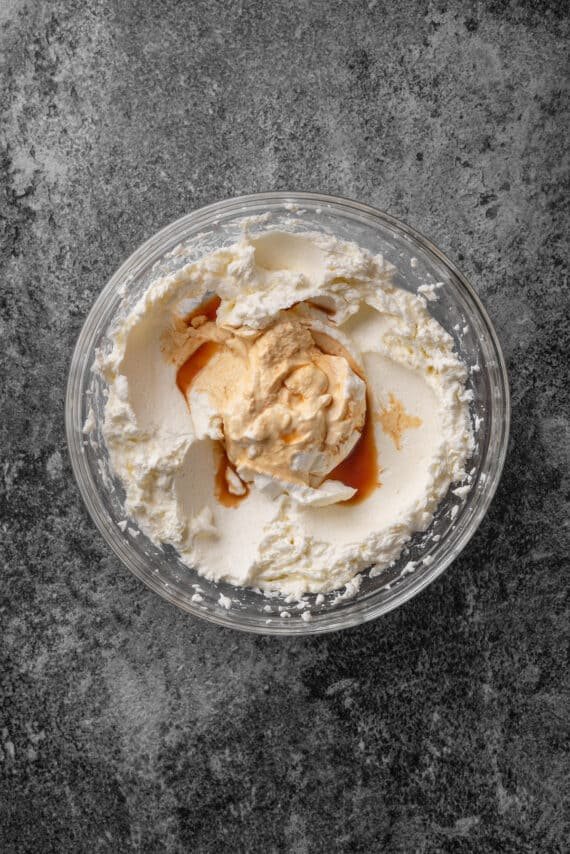 Vanilla added to cheesecake batter in a glass mixing bowl.