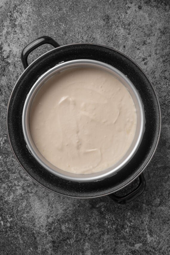 Cheesecake batter in a springform pan placed inside a larger pan with a water bath.