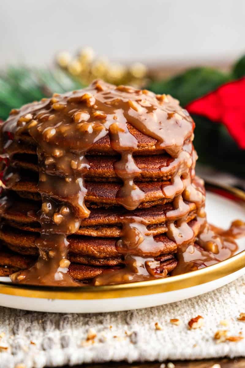 stack of gingerbread pancakes with butter pecan syrup drizzled on top on plate