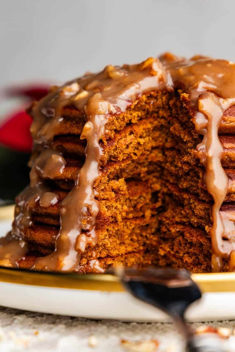 A stack of gingerbread pancakes with a section cut out so you can see the fluffy interior.